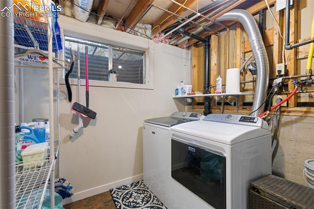 Image 37 of 45: Laundry area featuring independent washer and dryer and dark tile patterned