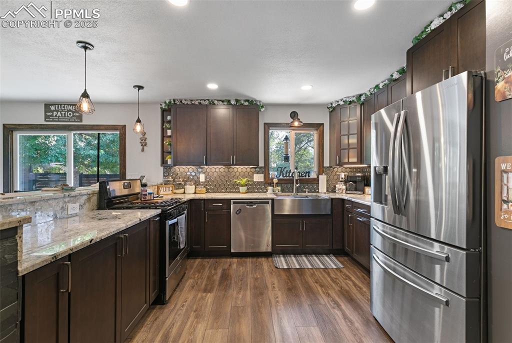 Image 6 of 45: Kitchen featuring dark brown cabinets, appliances with stainless steel fini