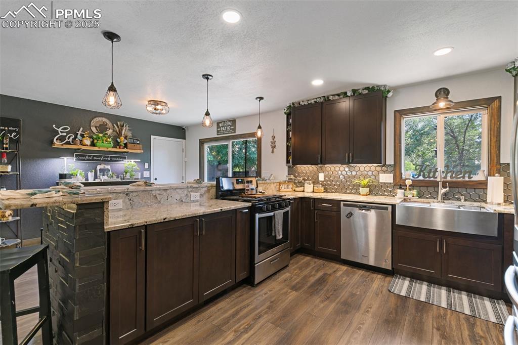 Image 7 of 45: Kitchen with dark brown cabinets, a peninsula, appliances with stainless st