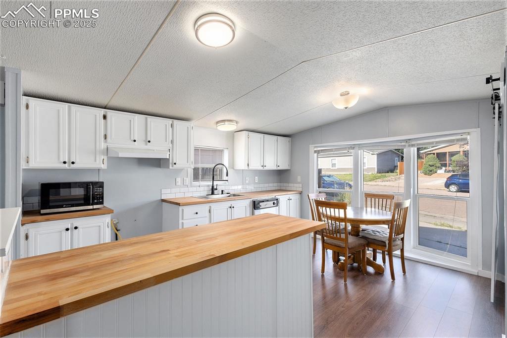 Image 10 of 18: Kitchen with white cabinets, dark wood finished floors, stainless steel mic