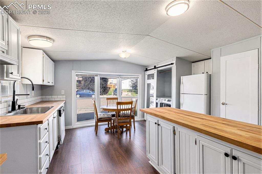 Image 11 of 18: Kitchen featuring wooden counters, a barn door, freestanding refrigerator, 