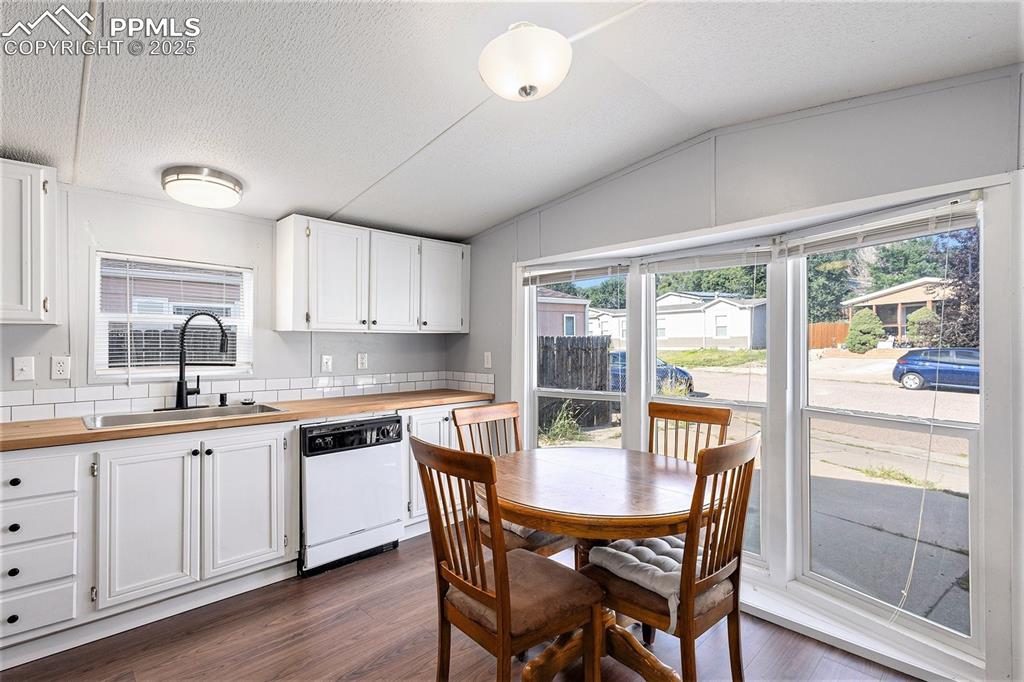Image 12 of 18: Kitchen with white cabinets, dark wood-type flooring, dishwasher, a texture
