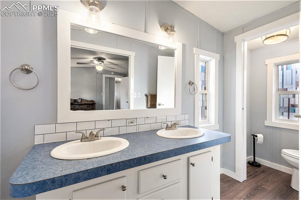 Image 15 of 18: Full bath featuring double vanity, tasteful backsplash, dark wood-type floo