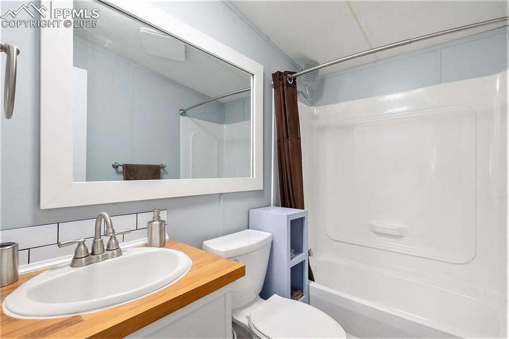 Image 18 of 18: Bathroom with shower / bathtub combination with curtain and vanity