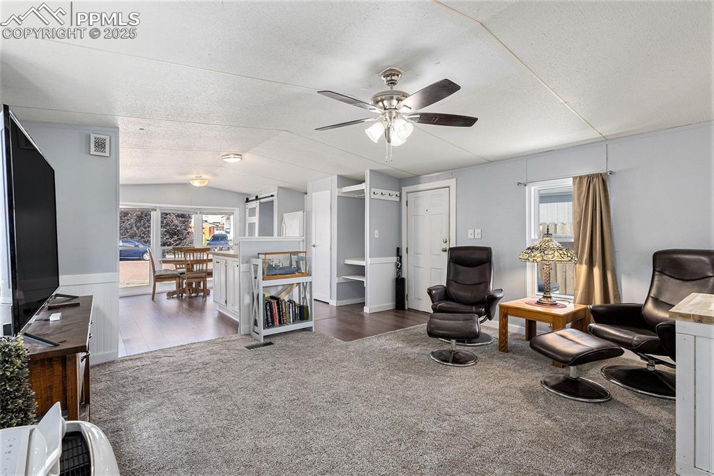 Image 5 of 18: Living area featuring vaulted ceiling, a textured ceiling, carpet flooring,