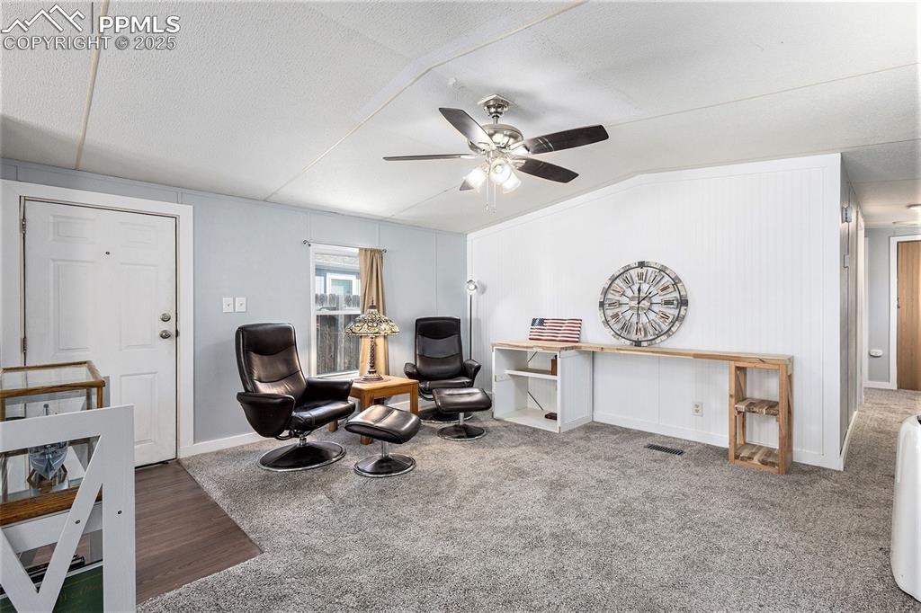 Image 6 of 18: Sitting room with lofted ceiling, carpet, ceiling fan, and a textured ceili