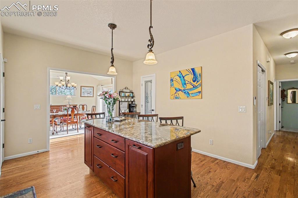Image 11 of 42: Kitchen with a breakfast bar area, light stone countertops, light wood-styl