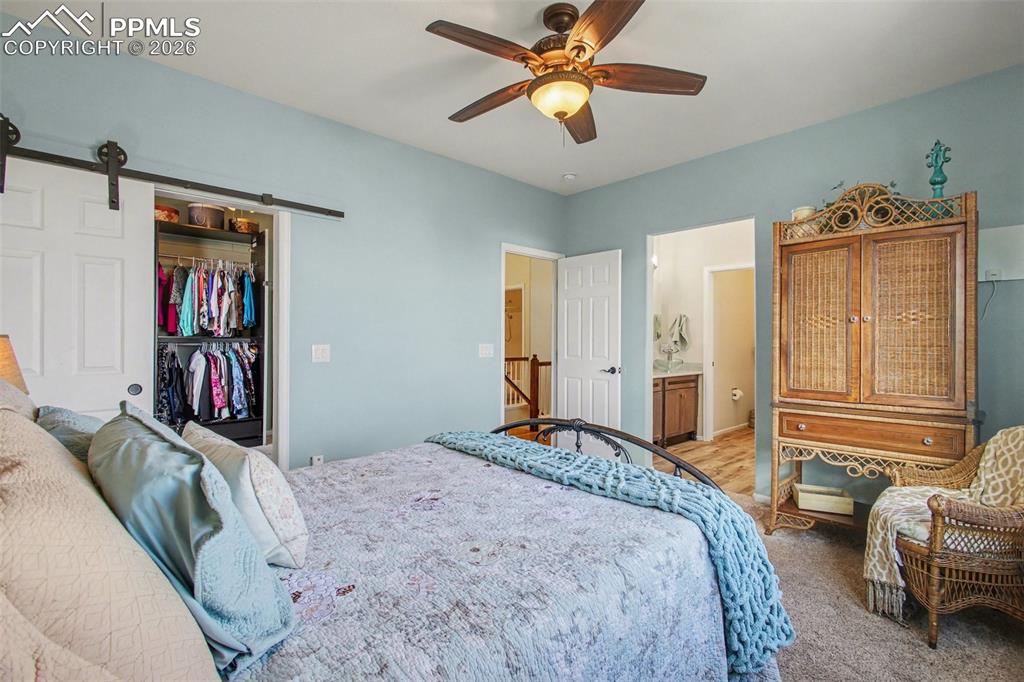 Image 18 of 42: Bedroom featuring a barn door, ceiling fan, a walk in closet, ensuite bath,