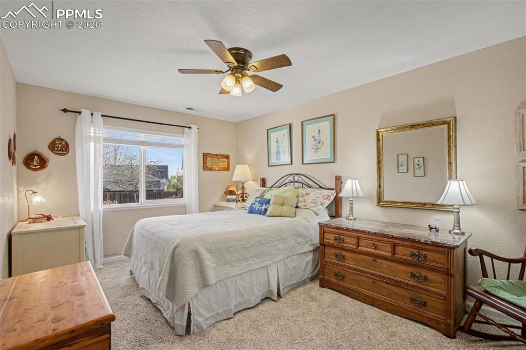 Image 22 of 42: Bedroom with light colored carpet and a ceiling fan