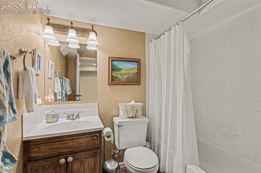 Image 24 of 42: Full bath with a textured wall, vanity, shower / bath combination with curt