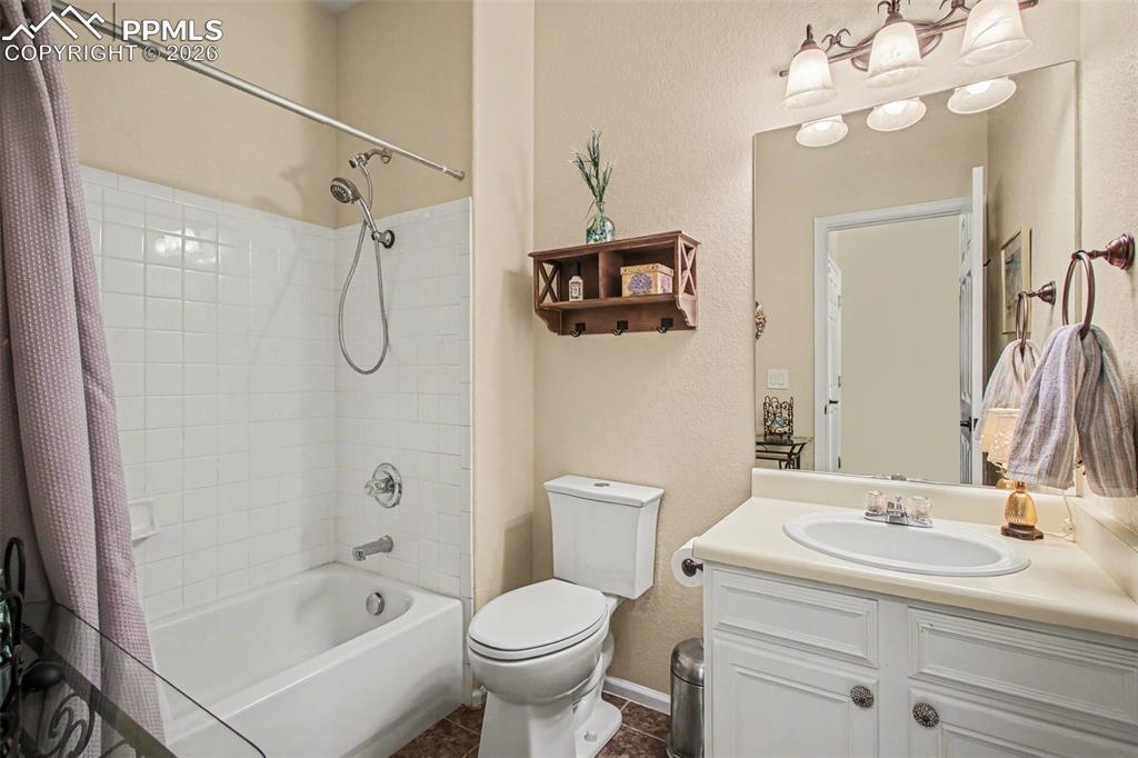 Image 25 of 42: Bathroom with vanity, shower / bath combo, a textured wall, and dark tile p