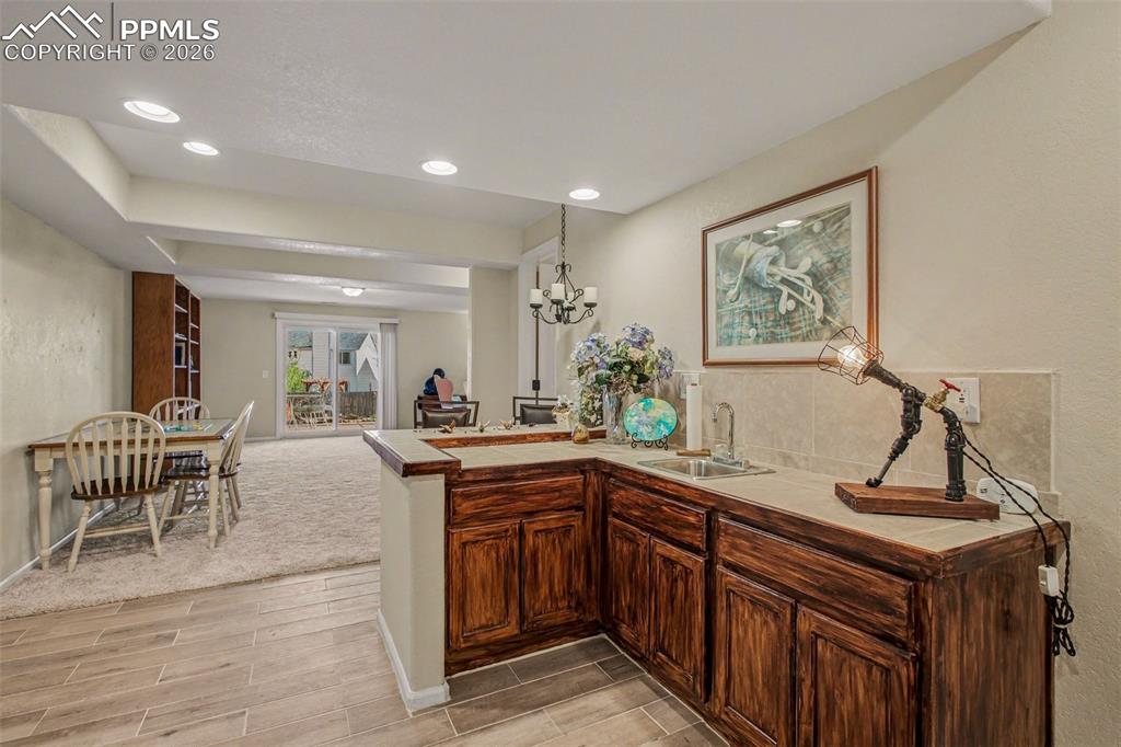 Image 31 of 42: Kitchen with a peninsula, wood finish floors, tile countertops, open floor