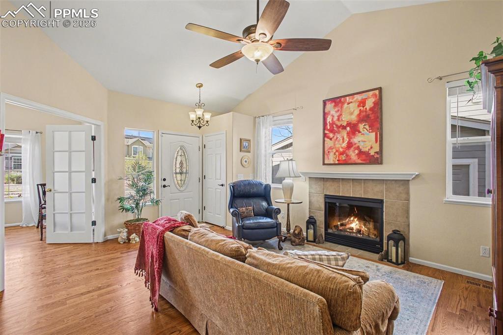 Image 4 of 42: Living area with a tiled fireplace, wood finished floors, lofted ceiling, a