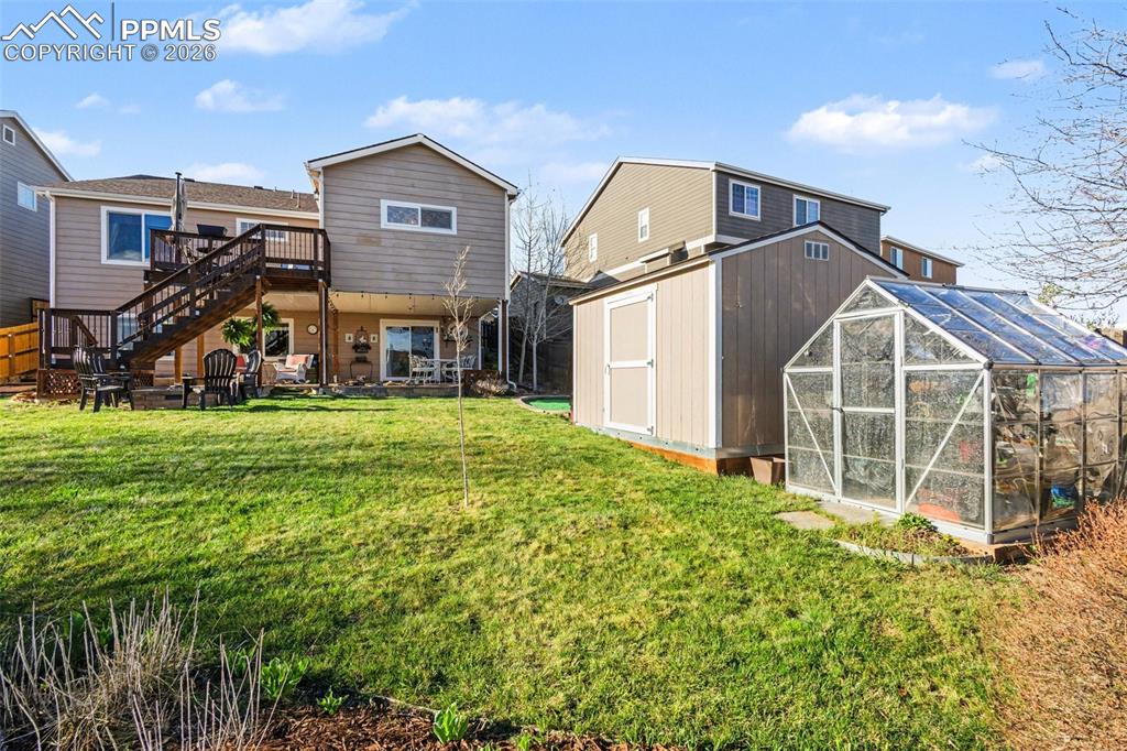 Image 41 of 42: Back of property featuring a storage shed, a greenhouse, a patio area, a la