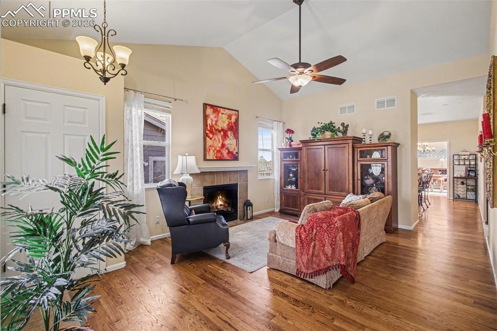 Image 5 of 42: Living room with wood finished floors, a fireplace, suspended lighting, and