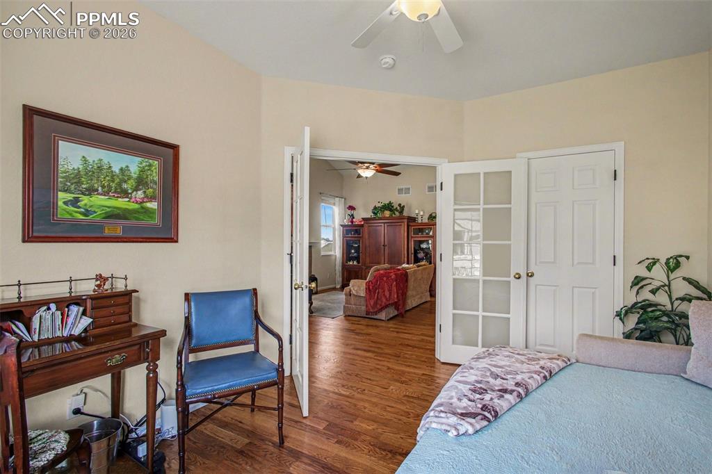 Image 7 of 42: Bedroom with dark wood-style floors, french doors, and ceiling fan