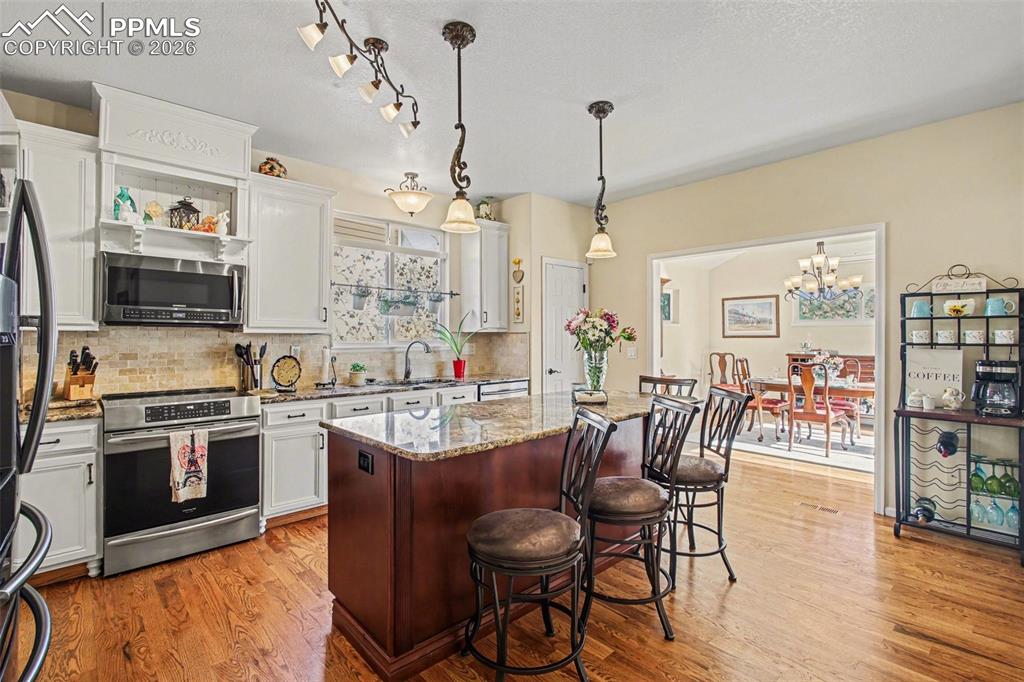 Image 8 of 42: Kitchen with stainless steel appliances, a kitchen breakfast bar, light sto
