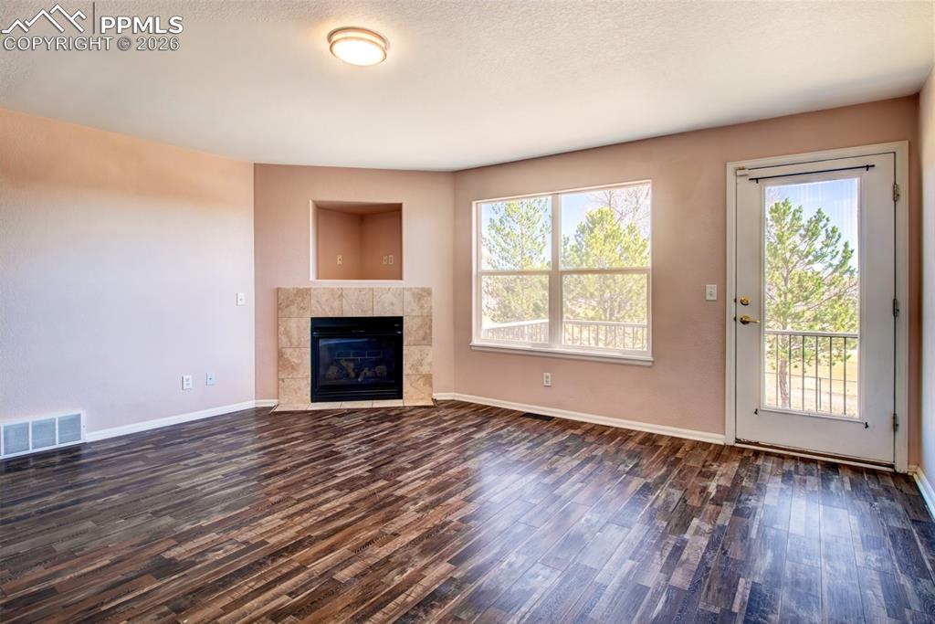 Image 12 of 33: Living room with LVP flooring, a gas fireplace and a walk out to deck