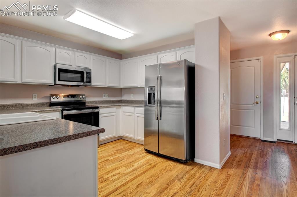 Image 4 of 33: Kitchen with wood floors, stainless steel appliances and ample cabinet spac