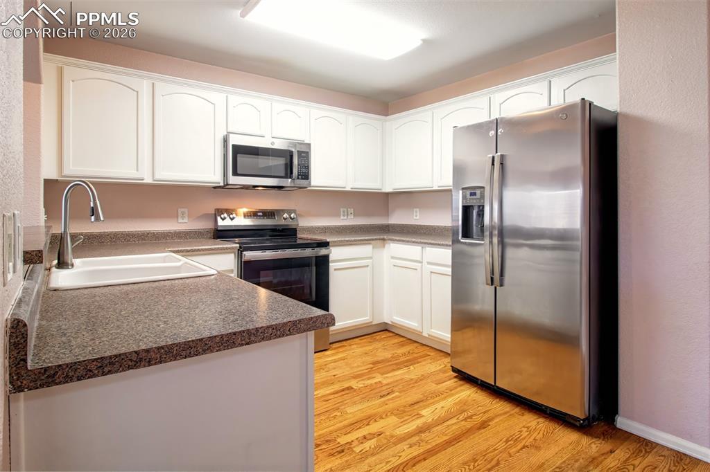 Image 6 of 33: Kitchen with wood floors, stainless steel appliances and ample cabinet spac
