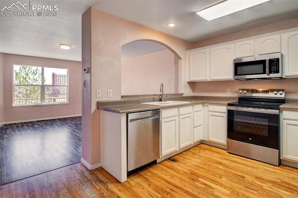 Image 7 of 33: Kitchen with wood floors, stainless steel appliances and ample cabinet spac