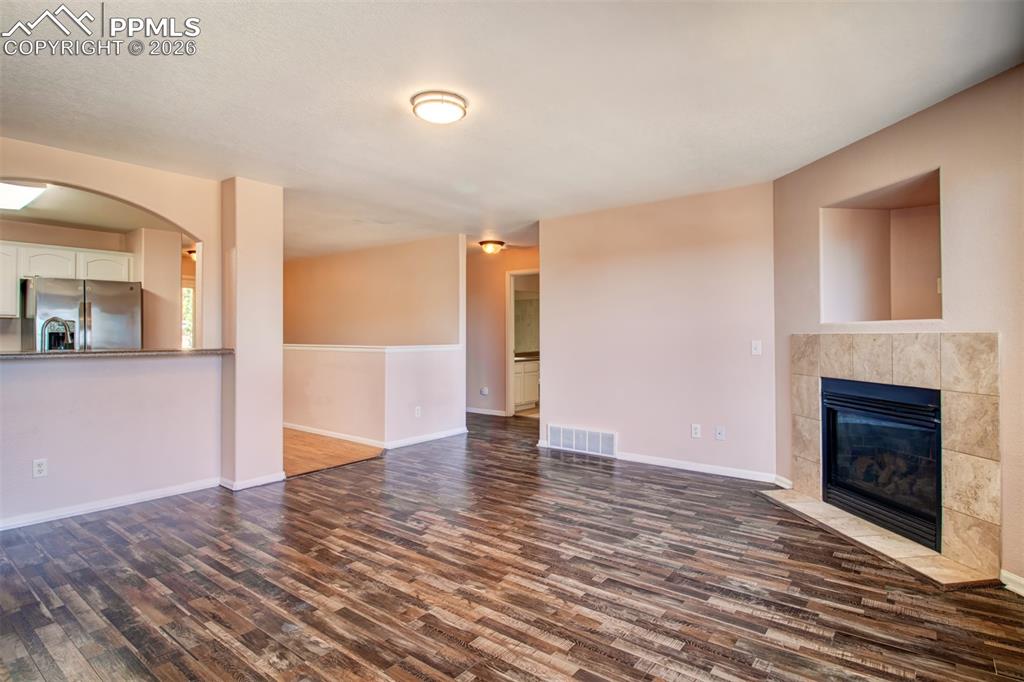 Image 8 of 33: Living room with LVP flooring, a gas fireplace and a walk out to deck