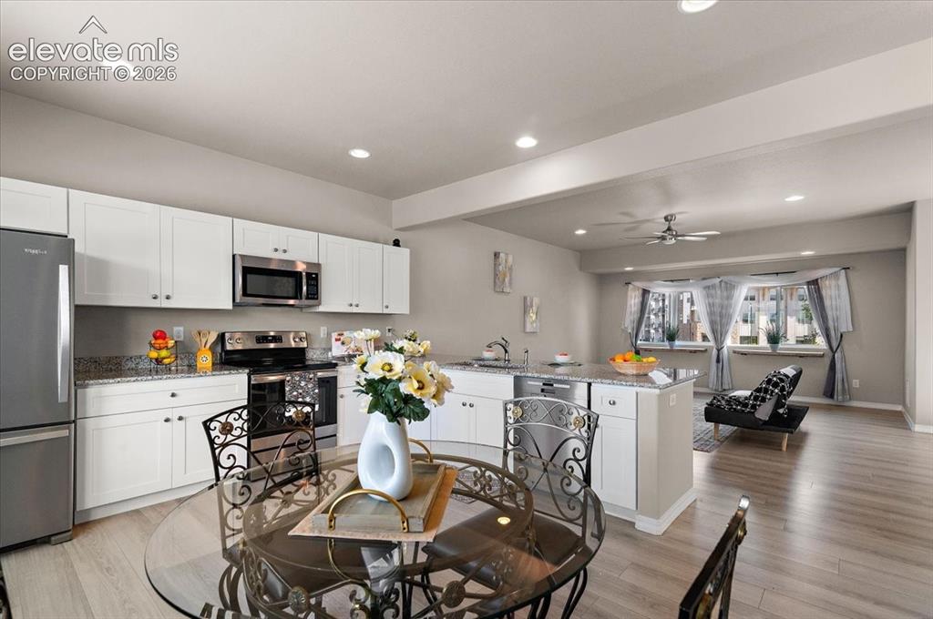 Image 10 of 31: Open-concept kitchen featuring white cabinetry, stainless steel appliances,