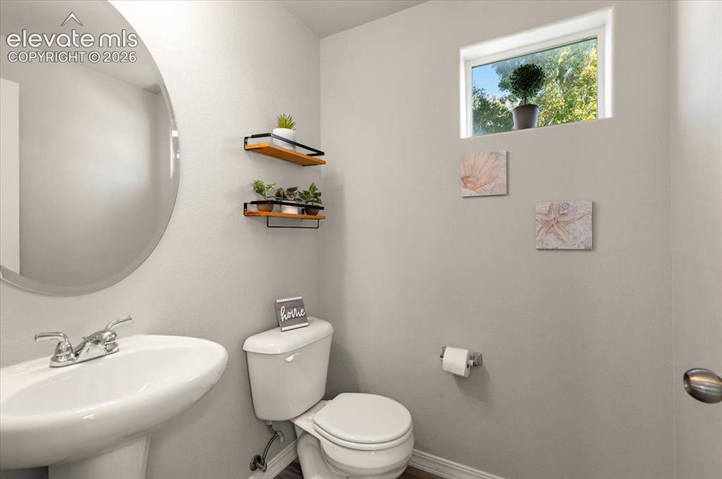 Image 15 of 31: Pedestal sink with chrome faucet, circular wall mirror, wall-mounted shelvi