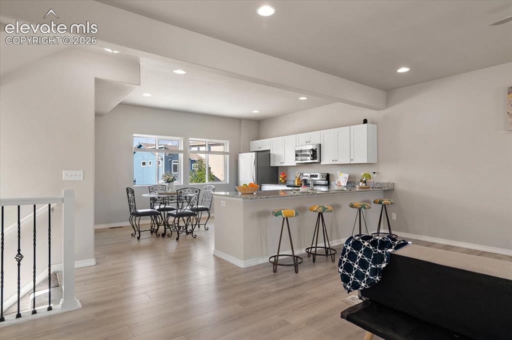 Image 17 of 31: Recessed lighting, wood-finish flooring, white cabinetry, stainless steel a