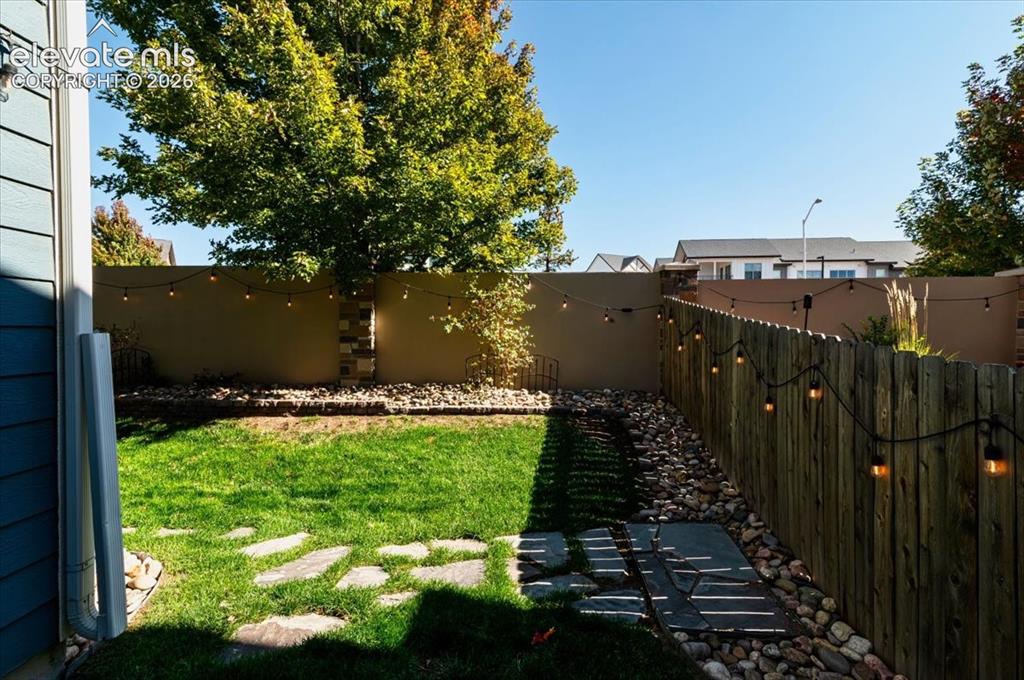 Image 29 of 31: Manicured lawn with flagstone stepping stones, natural wood fencing, and a