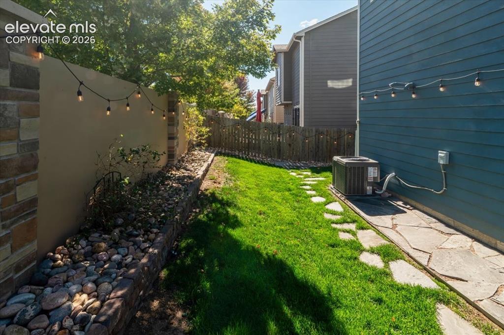 Image 30 of 31: Expansive side yard featuring a manicured lawn, flagstone pathway, and ston