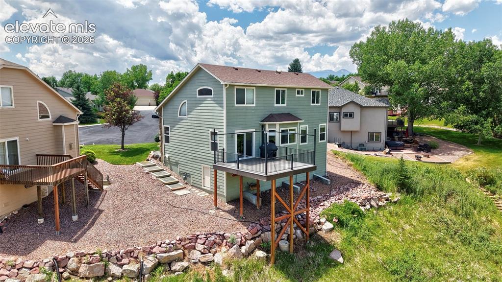 Image 12 of 50: Multi-level property featuring a large deck with dark railing, a ground-lev