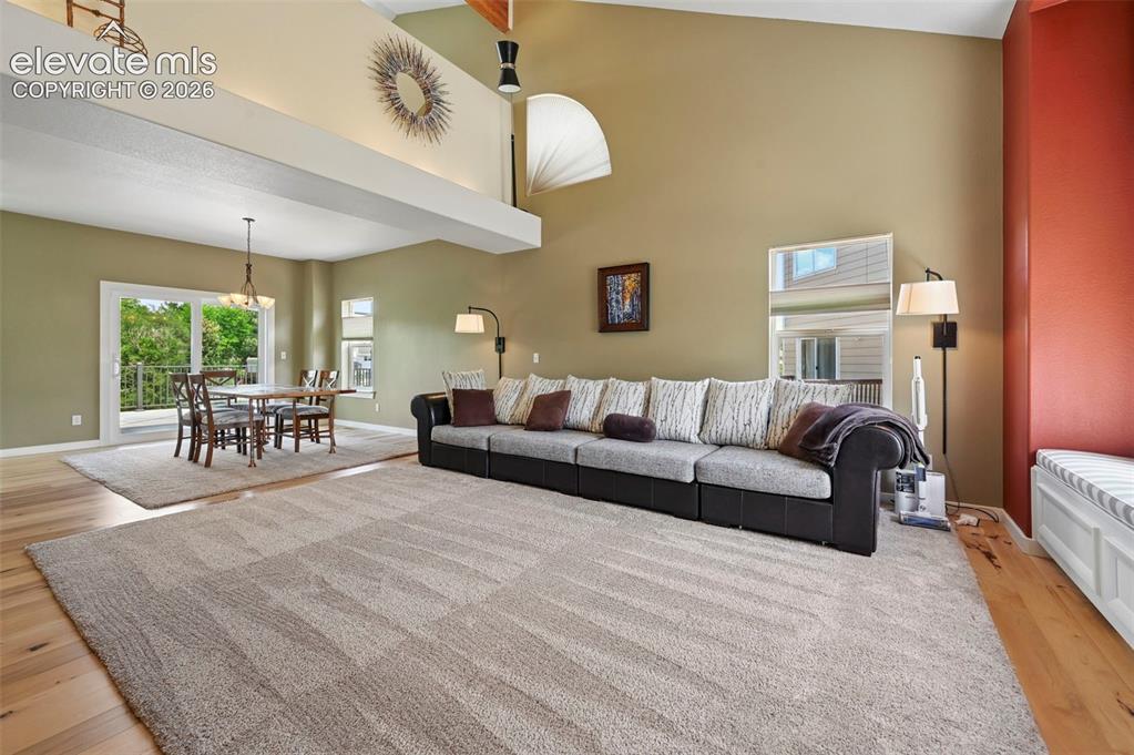 Image 17 of 50: Spacious living area featuring wood-finish flooring, a vaulted ceiling with