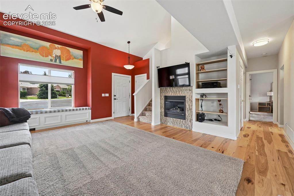 Image 18 of 50: Living area featuring a floor-to-ceiling fireplace with tile surround, buil
