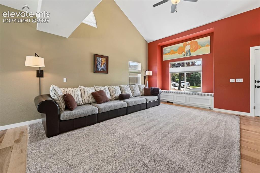 Image 19 of 50: Living area featuring vaulted ceilings, a large window with a built-in wind