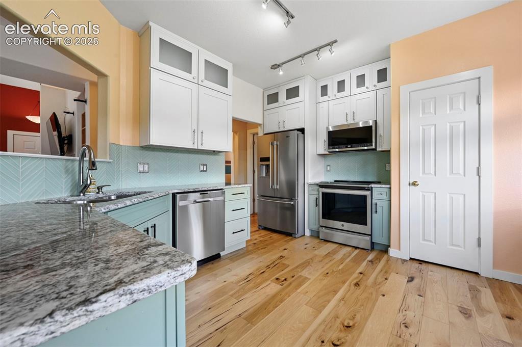 Image 23 of 50: Kitchen featuring light wood-finish flooring, light-colored upper cabinetry