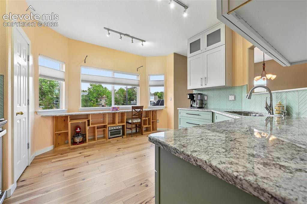 Image 25 of 50: Kitchen featuring light wood-finish flooring and a bay window area with bui