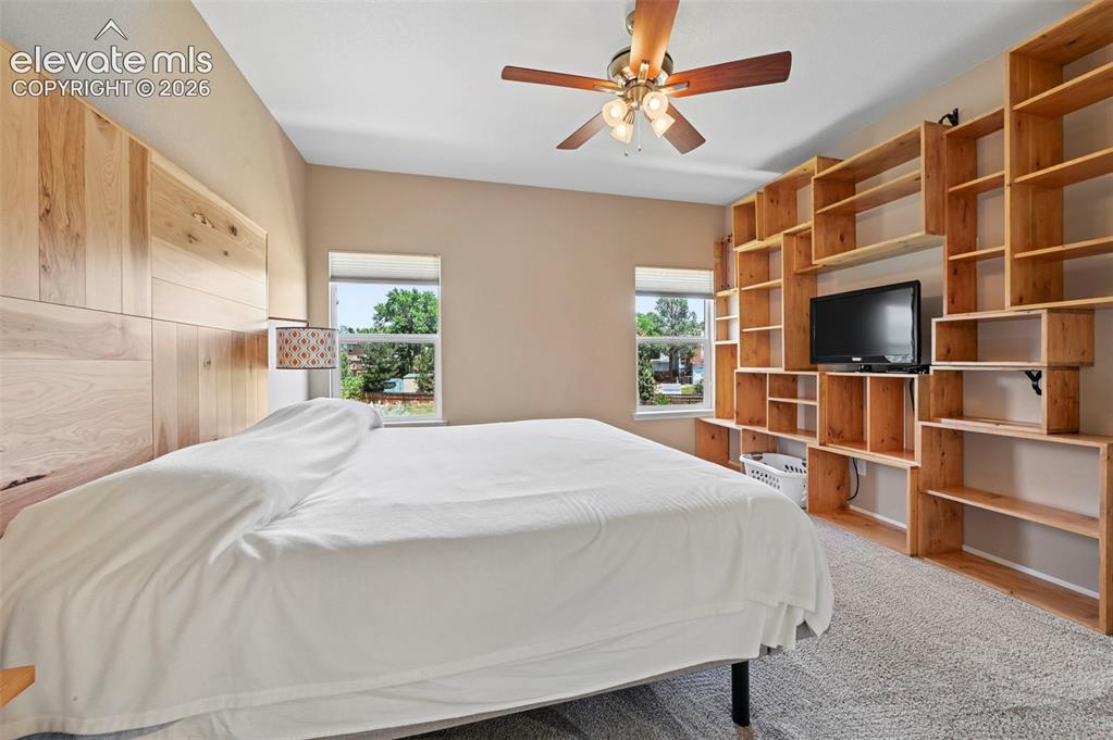 Image 28 of 50: Spacious room featuring a light wood panel accent wall, two windows providi