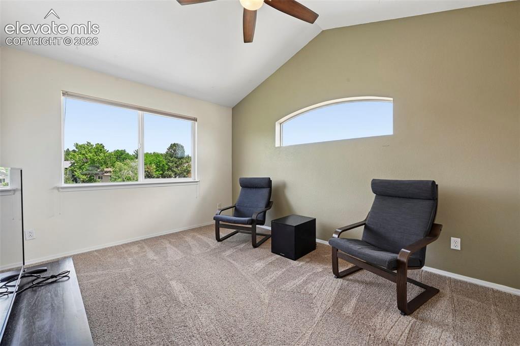 Image 33 of 50: Spacious room featuring vaulted ceilings, a ceiling fan, and neutral carpet