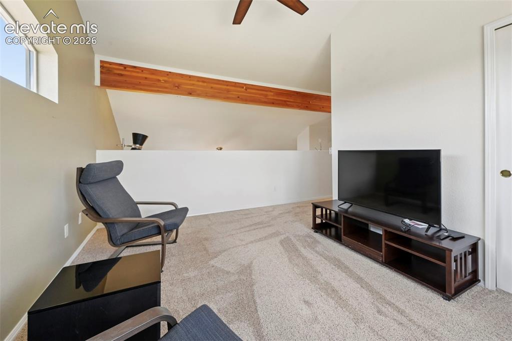 Image 35 of 50: Loft space featuring sloped ceilings, a prominent exposed wood beam, and a