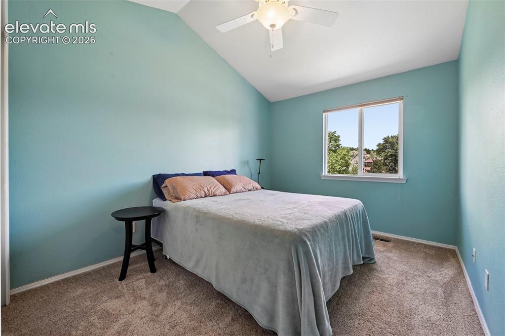 Image 37 of 50: Vaulted ceiling room with an overhead fan, carpet flooring, and a large win