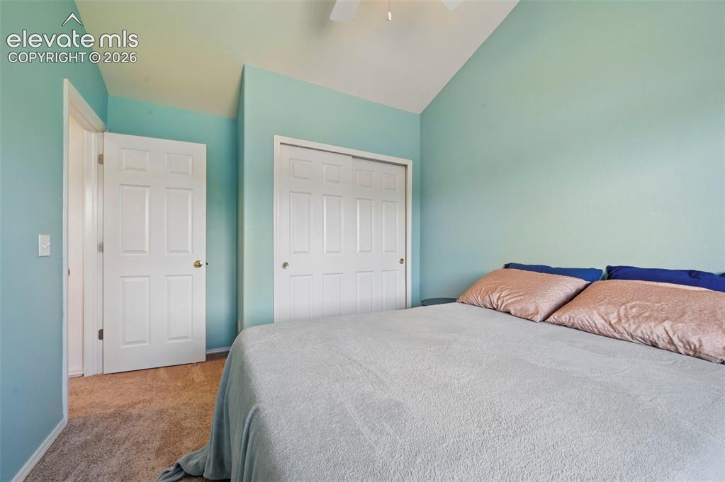 Image 38 of 50: Carpeted bedroom featuring a vaulted ceiling with a ceiling fan, a paneled