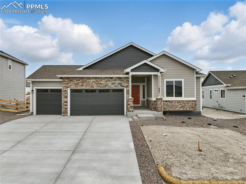 Caption: Craftsman inspired home featuring concrete driveway, stone siding, a shingled roof, fence, and a gar
