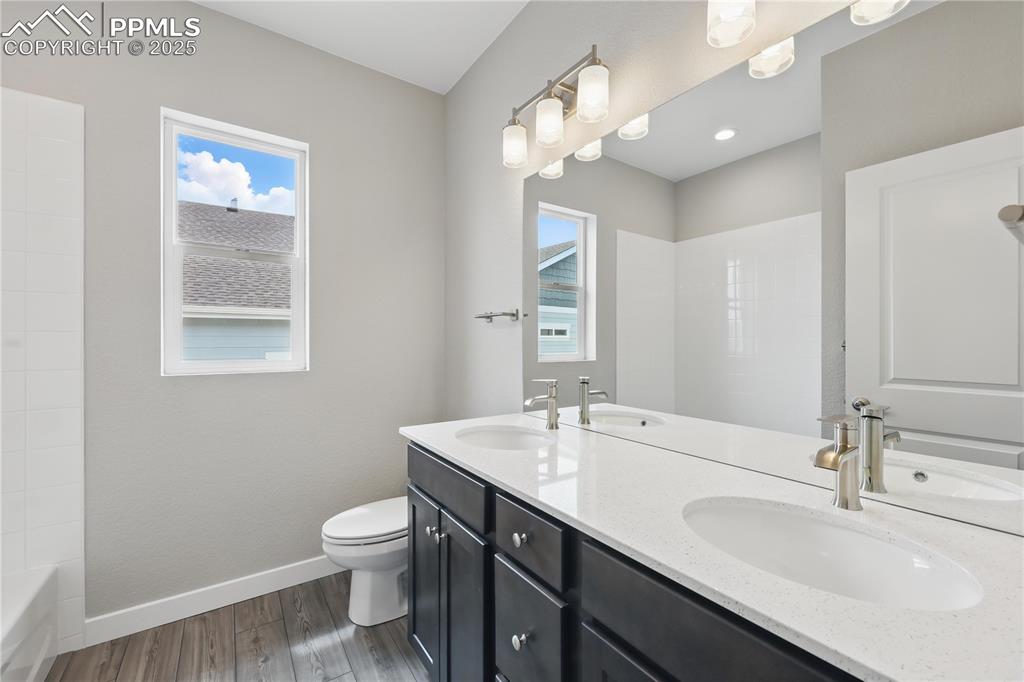 Image 12 of 35: Full bath with toilet, a sink, wood finished floors, and baseboards