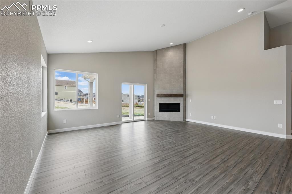 Image 17 of 35: Unfurnished living room with dark wood-style floors, a tile fireplace, rece