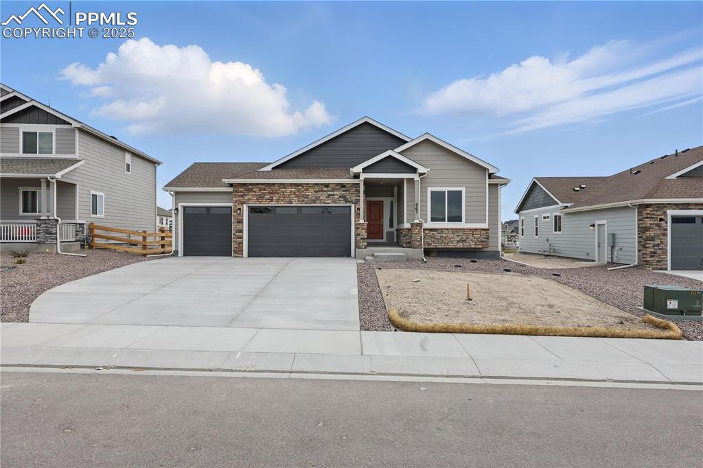 Image 2 of 35: Craftsman inspired home with driveway, fence, an attached garage, and stone
