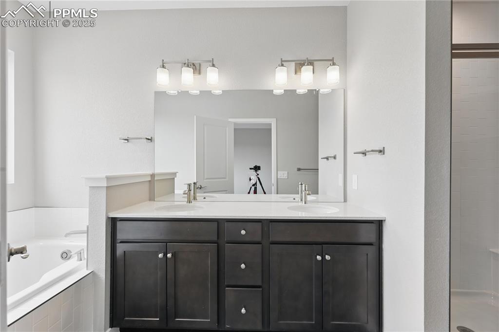 Image 21 of 35: Bathroom featuring tiled shower, double vanity, a bath, and a sink