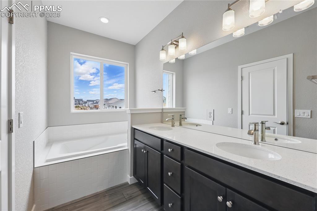 Image 22 of 35: Bathroom with wood finished floors, a garden tub, and a sink