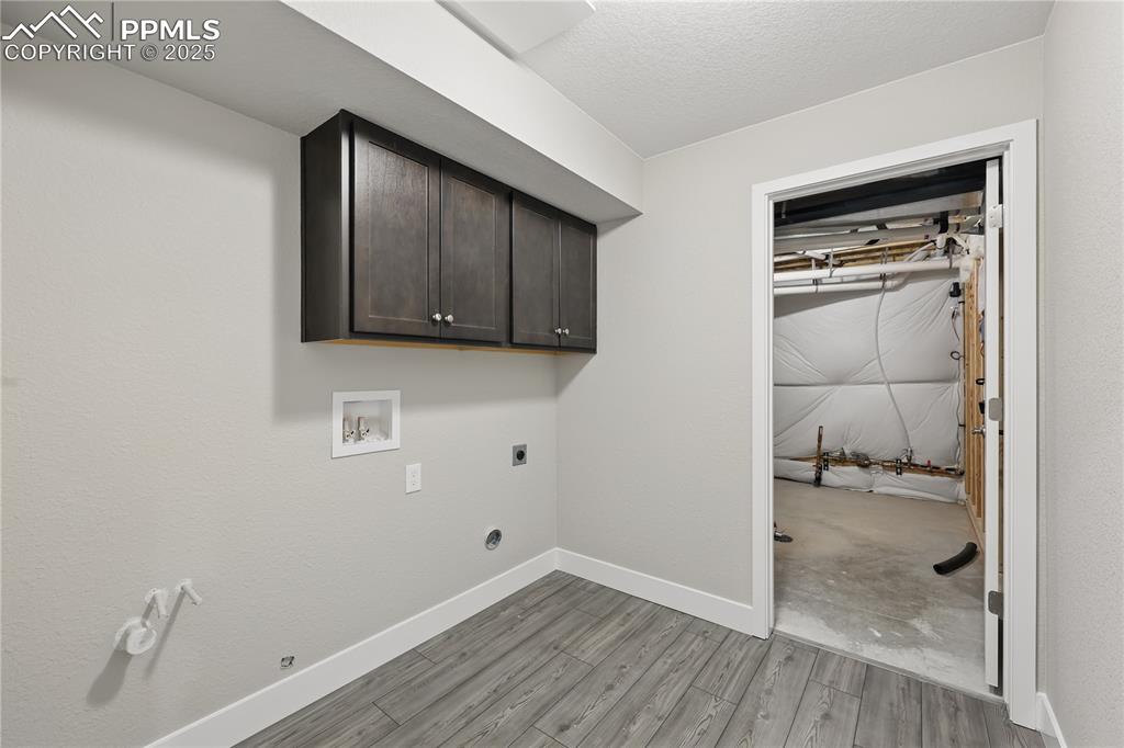 Image 28 of 35: Washroom featuring cabinet space, light wood-style floors, hookup for a gas