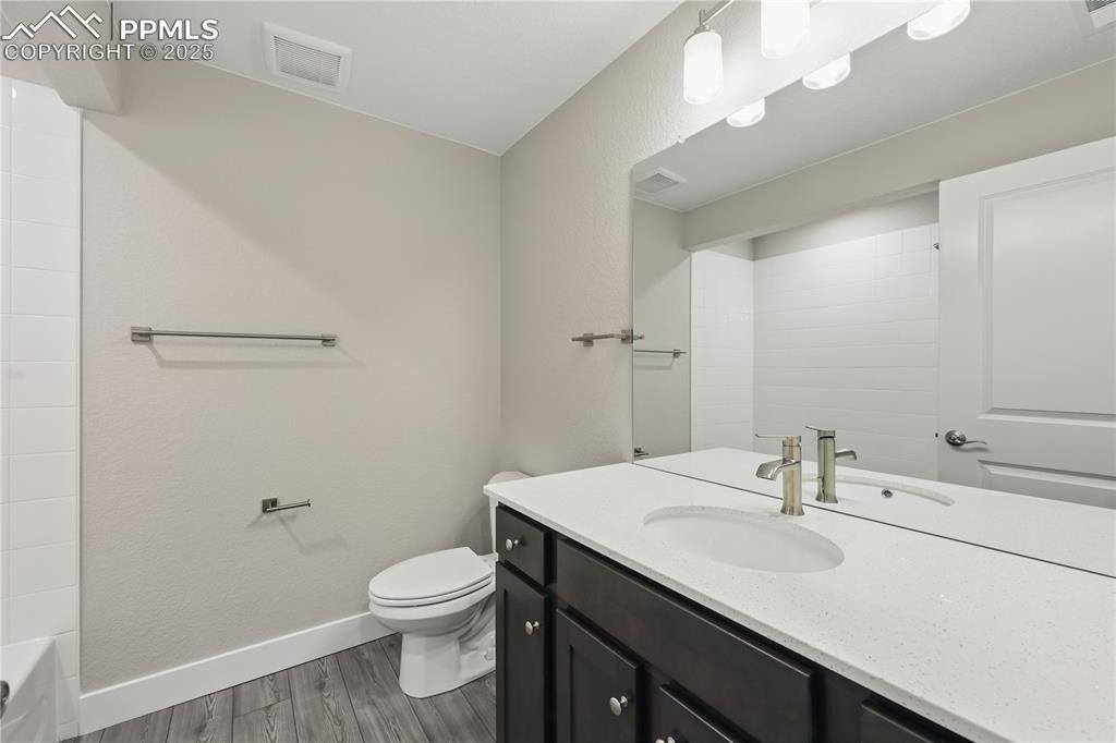 Image 30 of 35: Full bath with visible vents, baseboards, toilet, wood finished floors, and